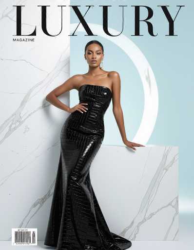 A polished ethnic woman in a sleek black crocodile mink-blend dress commands attention on the cover of Luxury magazine. She poses against a white marble infinity wall with pastel accents, bathed in soft studio lighting. The high-key fashion photography style emphasizes elegance and sophistication.